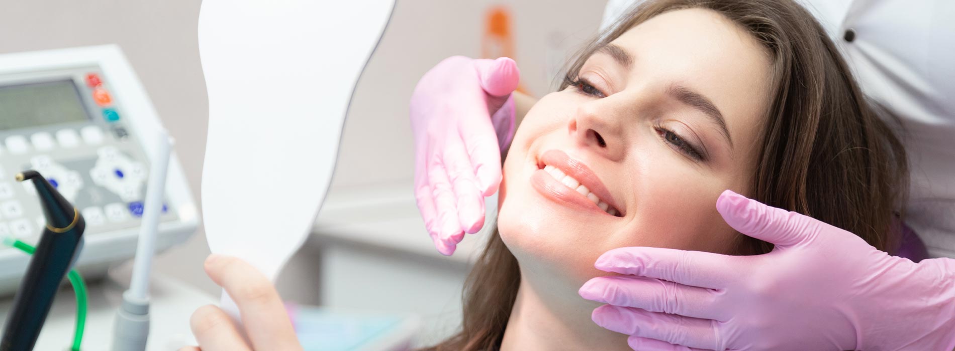 The image is a photograph of a woman with light skin, smiling at the camera. She appears to be in her late twenties or early thirties and has long hair. Her eyes are looking directly at the camera, and she is holding up her index finger near her mouth as if she s making a point or emphasizing something. The background is plain and light-colored, which suggests that this could be a stock photo used for various purposes such as advertising, personal branding, or lifestyle content.