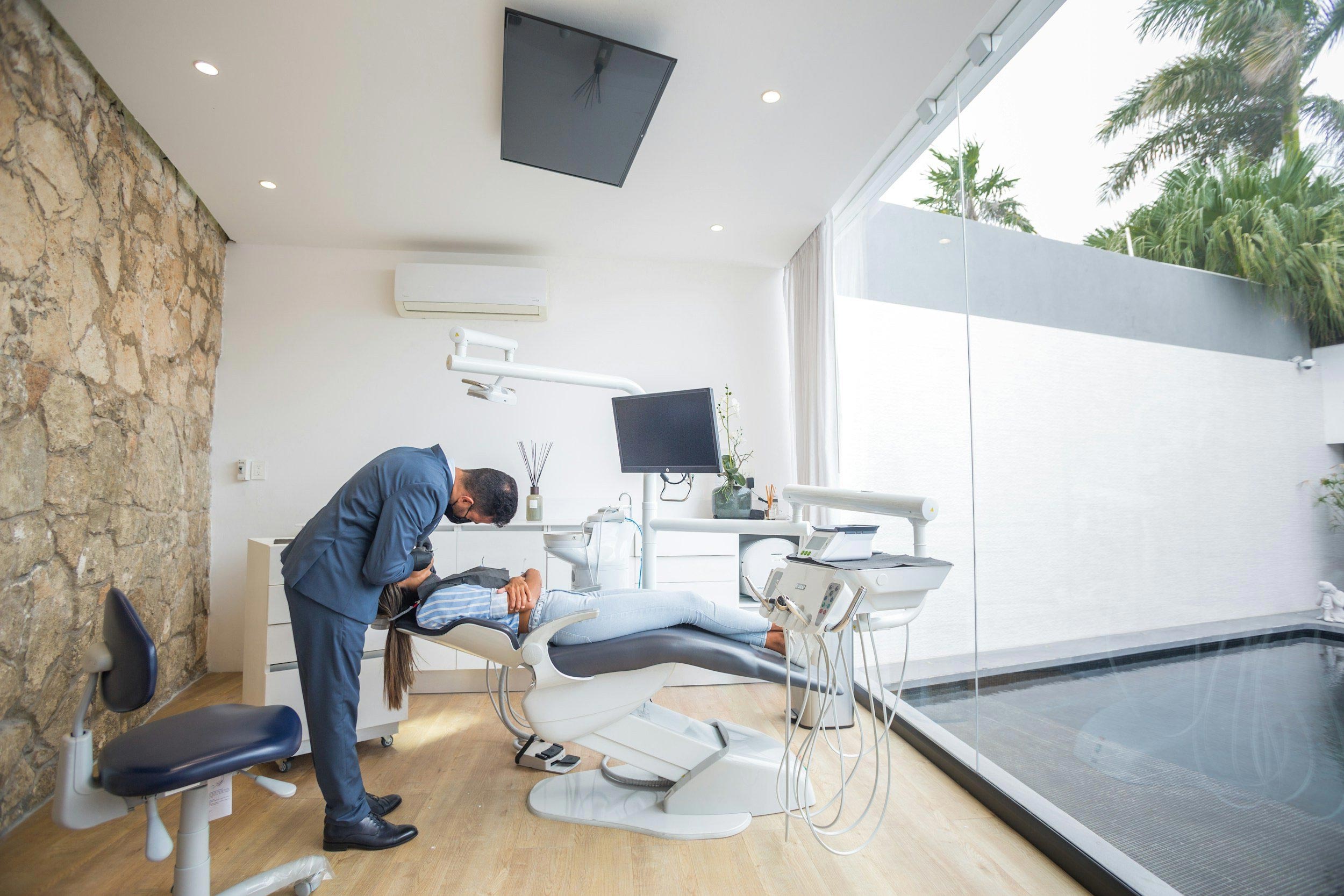 A modern dental practice with a blue and white chair, a dental treatment table, and medical equipment.