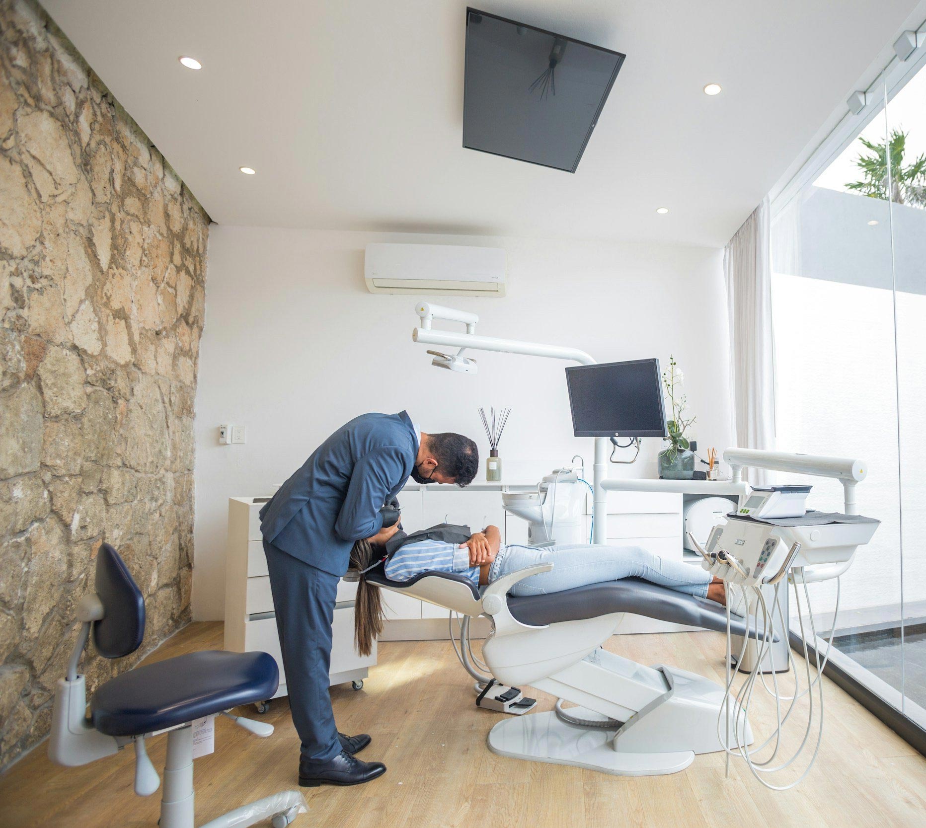 The image shows a modern dental or medical office interior with a dental chair, equipment, and a clean, professional environment.